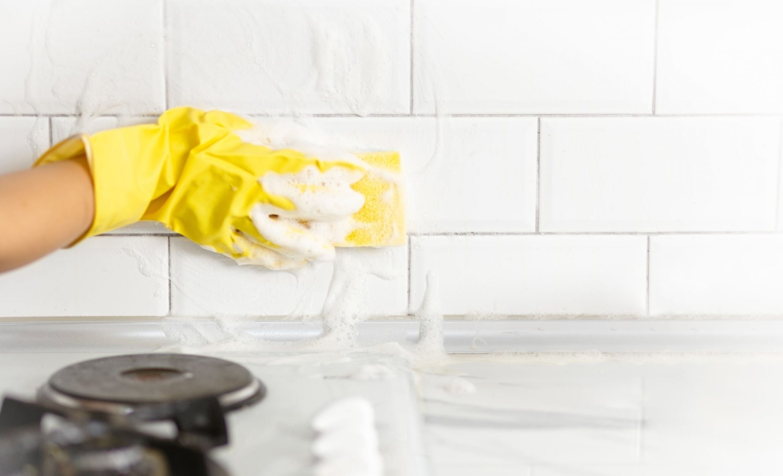 Hand and glove cleaning the kitchen tiles