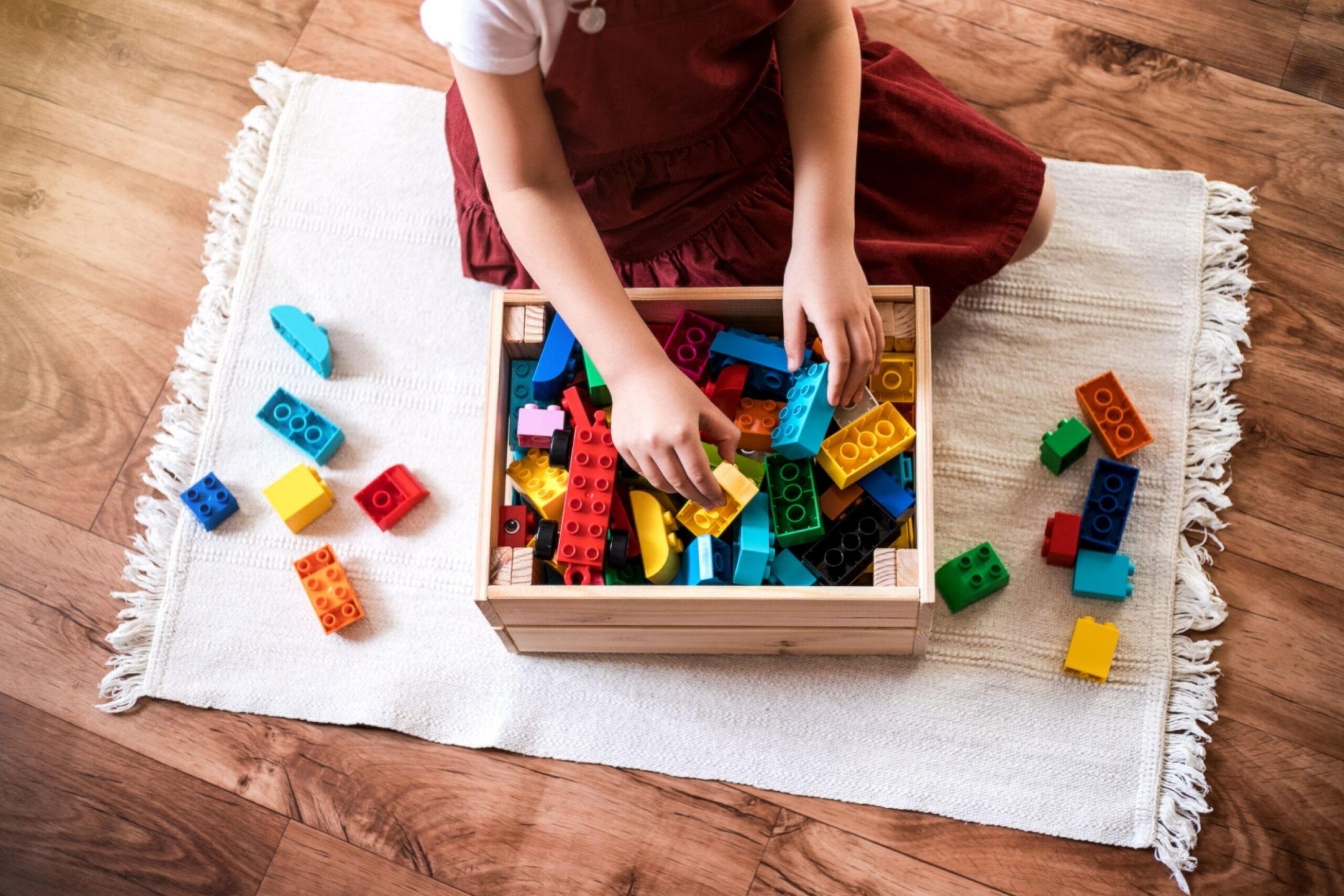 Little girl cleaning up the toy box at home