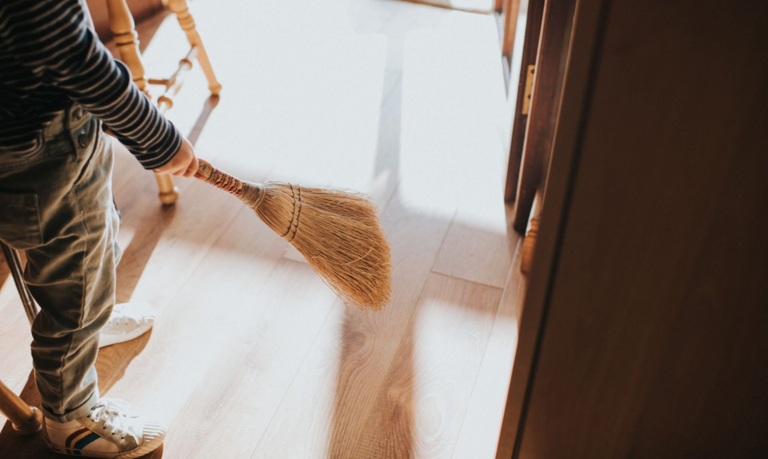 Child sweeps with a traditional small brush.